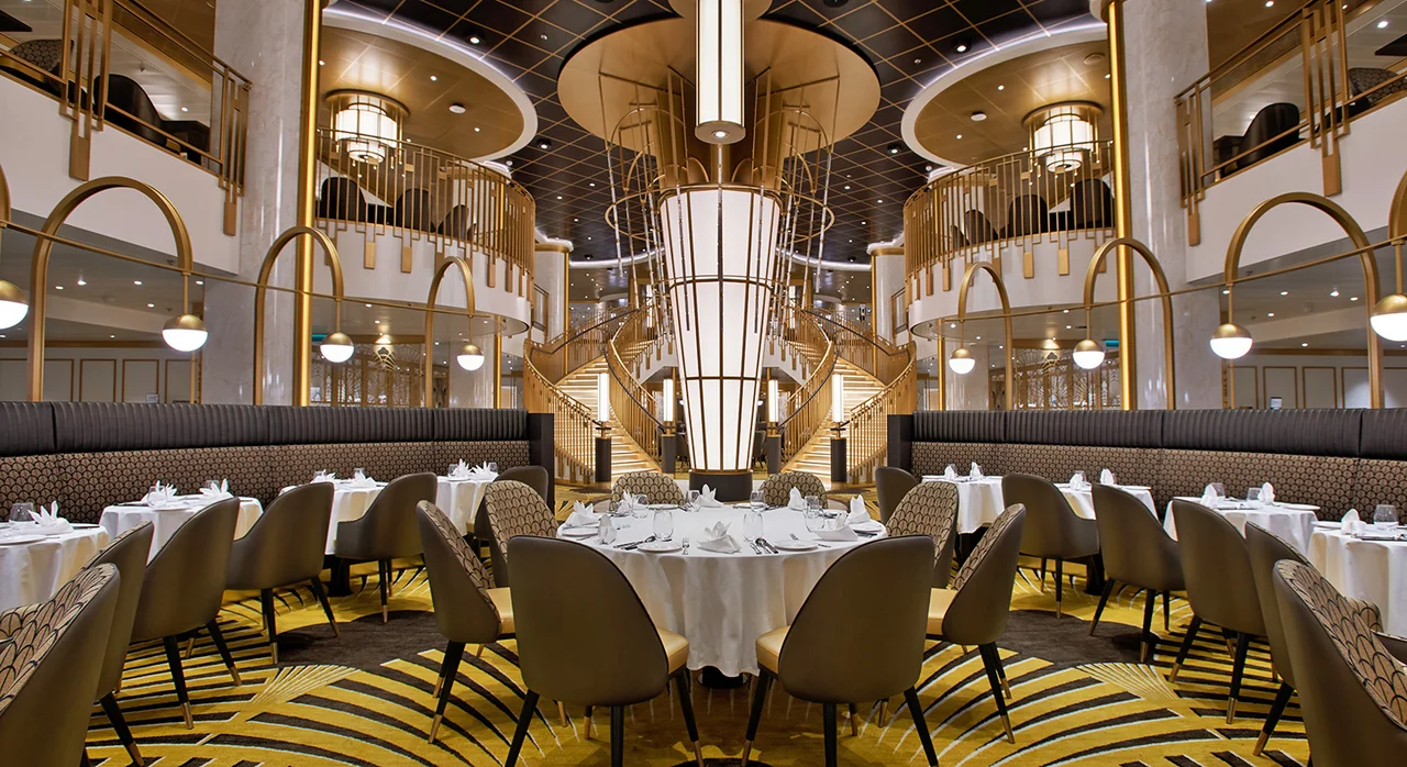 Grand Restaurant на Adora Magic City: двухуровневый зал с золотистой лестницей и сервированными столами